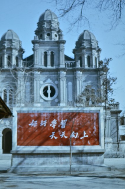 Плакат с комунистически лозунги пред Католическата катедрала в Пекин