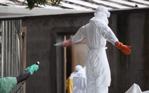 Медицинска сестра в Либерия, облечена в предпазни дрехи, се дезинфекцира